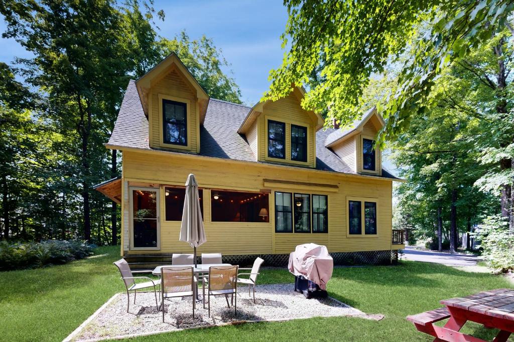 a yellow house with a table and chairs in front of it at The Mitchell House in North Woodstock