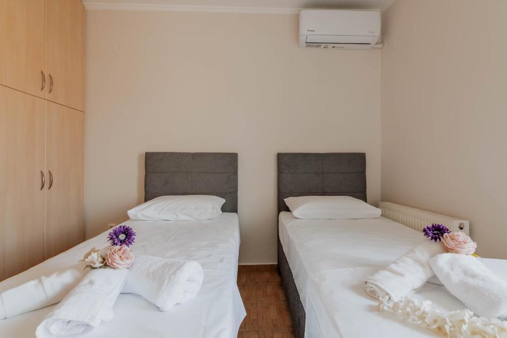 two beds in a room with white sheets and purple flowers at Elia House Nafplio in Nafplio