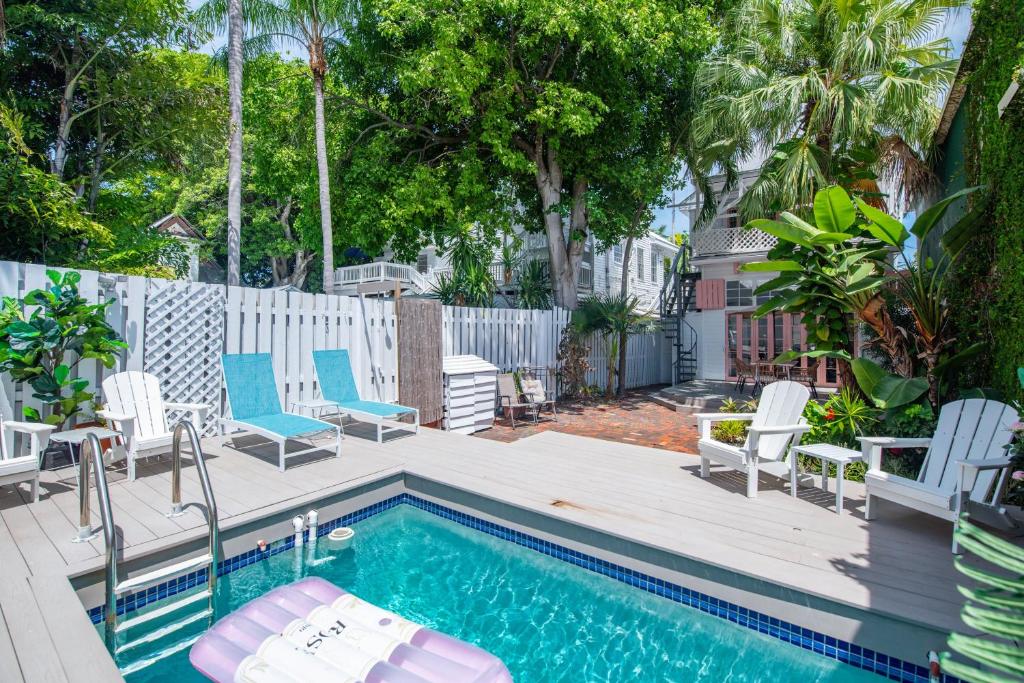 a backyard with a swimming pool with chairs and a deck at New Rose Retreat - Pool & Parking in Key West