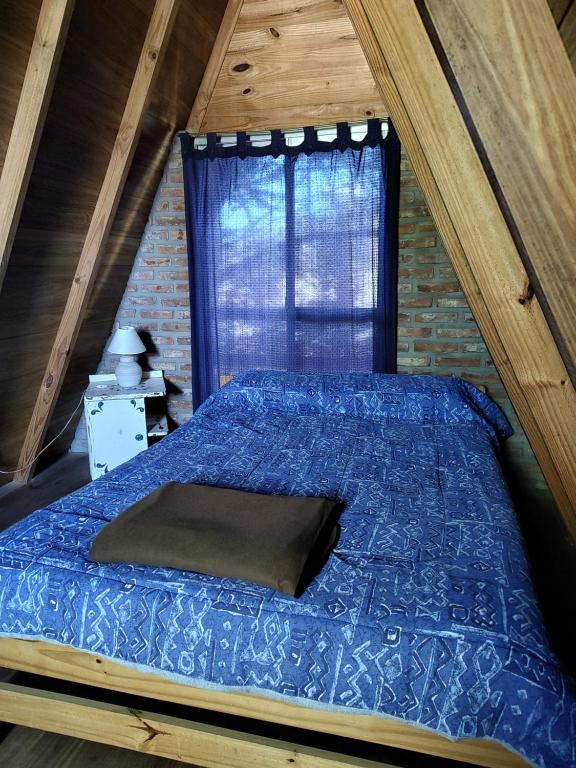 ein Bett mit einer blauen Bettdecke in einem Zimmer mit einem Fenster in der Unterkunft Cabañas Alpinas San Pedro in San Pedro