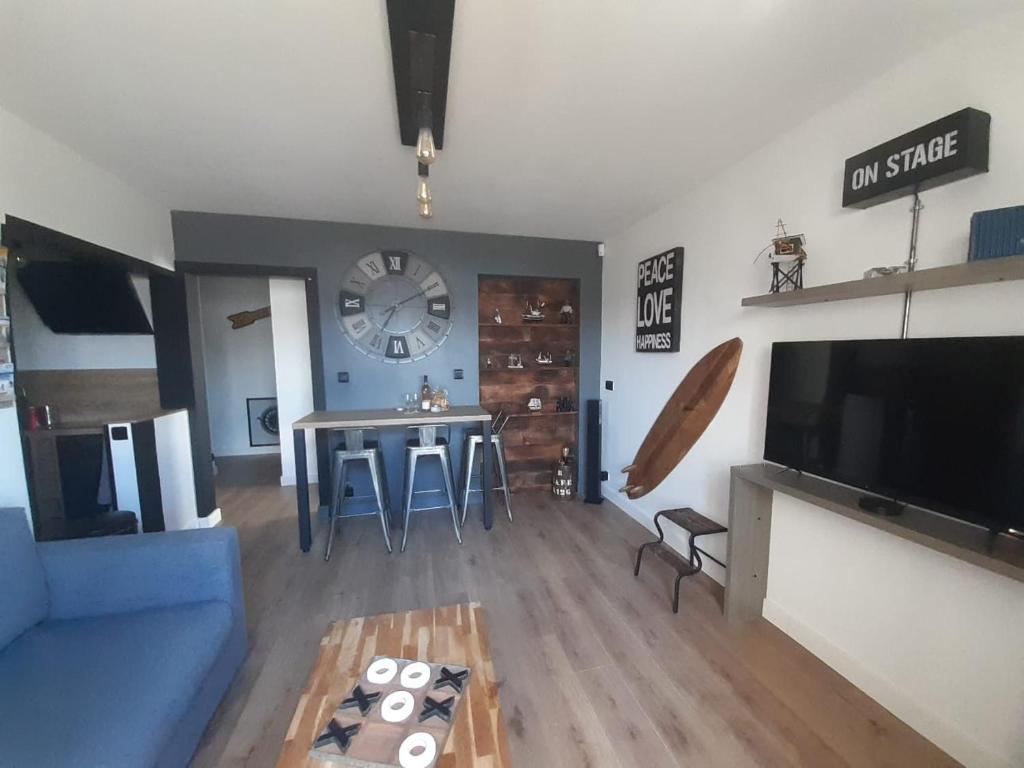 un salon avec un canapé bleu et une table dans l'établissement Appartement terrasse Vendée Globe, à Les Sables-dʼOlonne