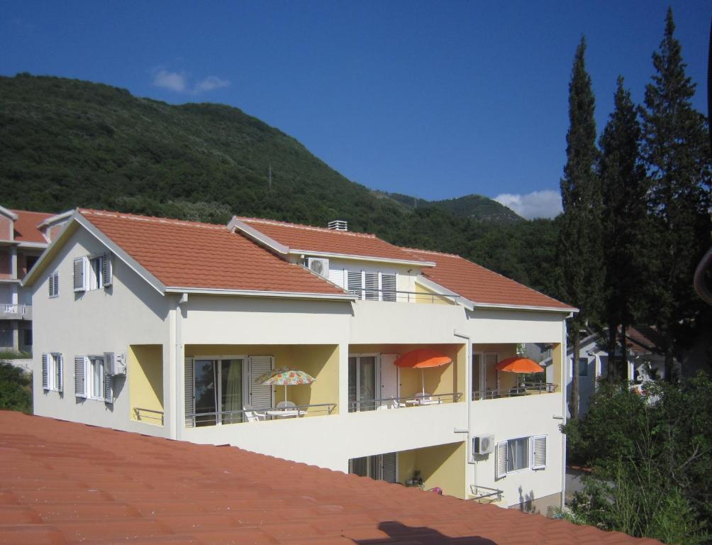 a building with orange umbrellas in front of a mountain at Apartments Viktoria in Tivat