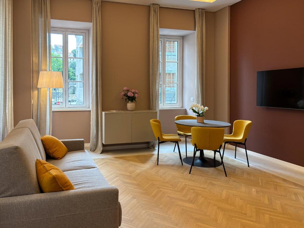 a living room with a couch and a table and chairs at HOMEY I Teatro Romano Apartments in Trieste