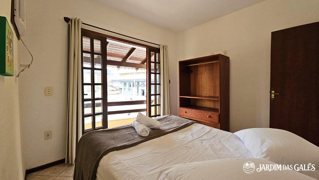 a bedroom with a bed and a large window at Jardim das Gales Bombinhas in Bombinhas