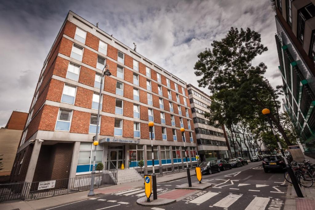 a large brick building on a city street with cars at LSE Carr-Saunders Hall in London