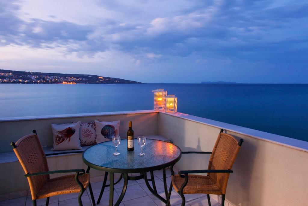 - une table et des chaises sur un balcon avec une bouteille de vin dans l'établissement Minos Apartments & Studios, à Siteía