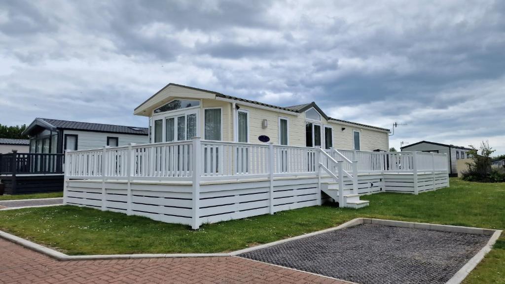 ein Haus mit einem weißen Zaun im Hof in der Unterkunft The Knightsbridge, Boulevard, Seal Bay Resort in Selsey