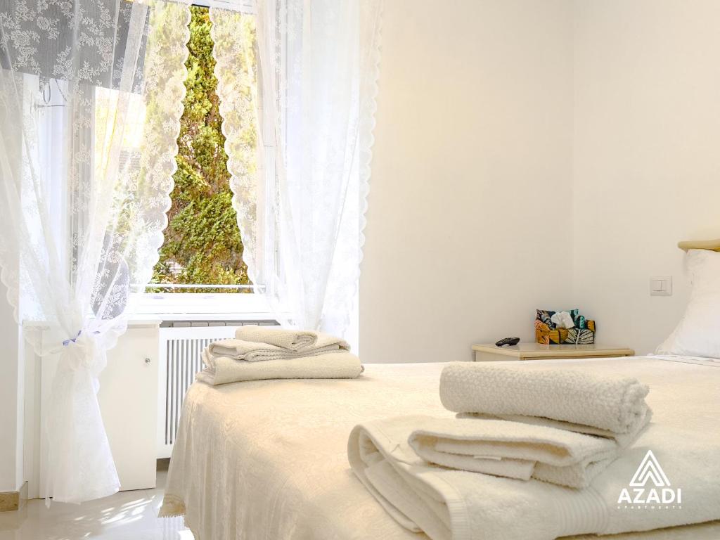 a white bedroom with a bed with towels on it at Azadi B&B Flaminio in Rome