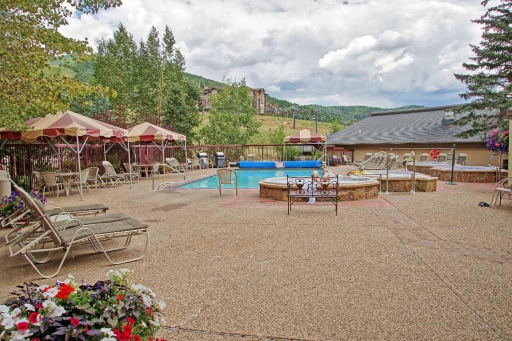 a patio with a pool and tables and chairs at Pool and Hot Tubs, Private Washer & Dryer, Creekside Base Area Location in Steamboat Springs