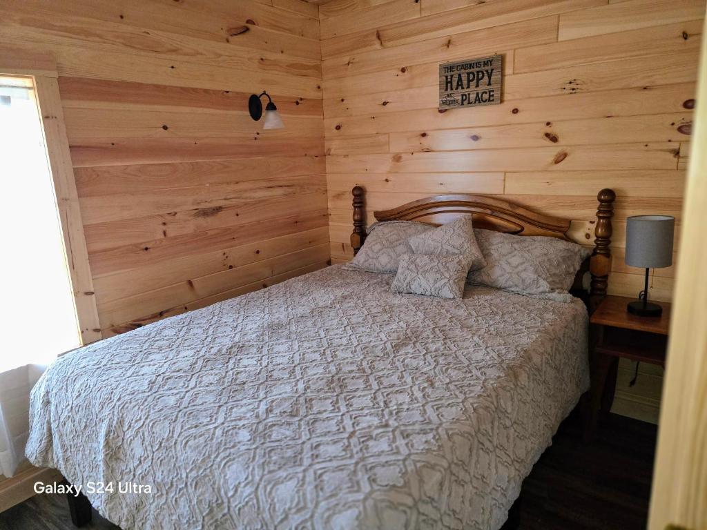 a bedroom with a bed with a wooden wall at Letchworth Valley Campground Cabins in Bliss