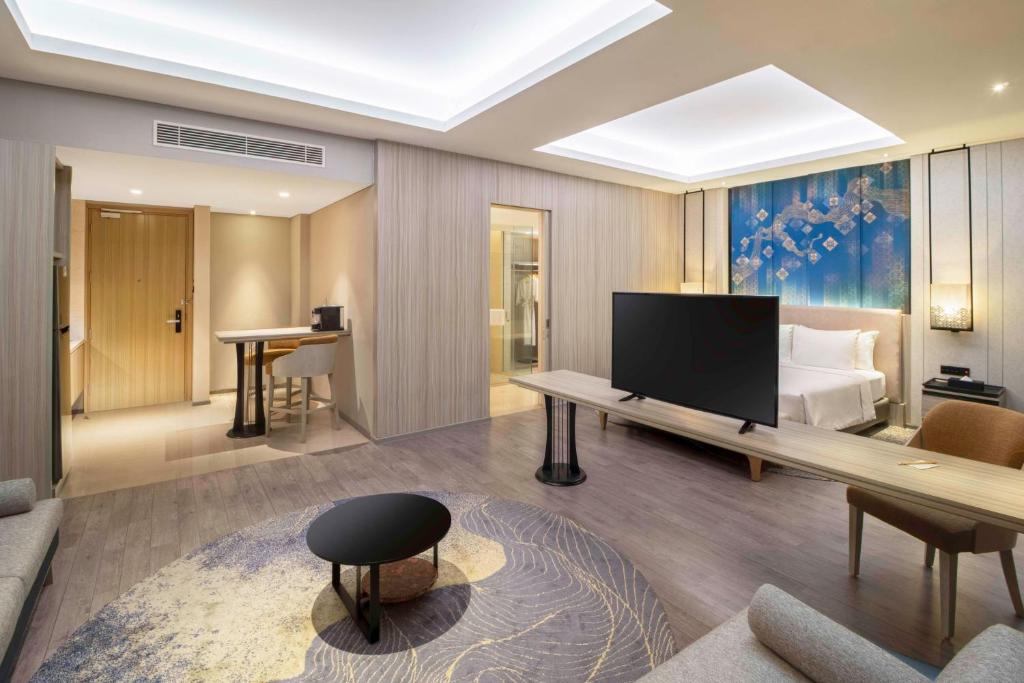a living room with a television and a bed at Radisson Lampung Kedaton in Bandar Lampung