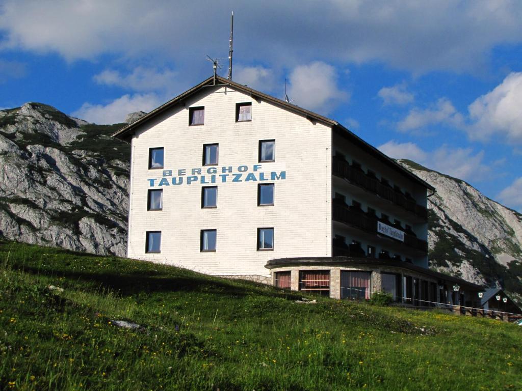 un edificio en la cima de una colina con una montaña en Hotel Berghof Tauplitzalm, en Tauplitzalm