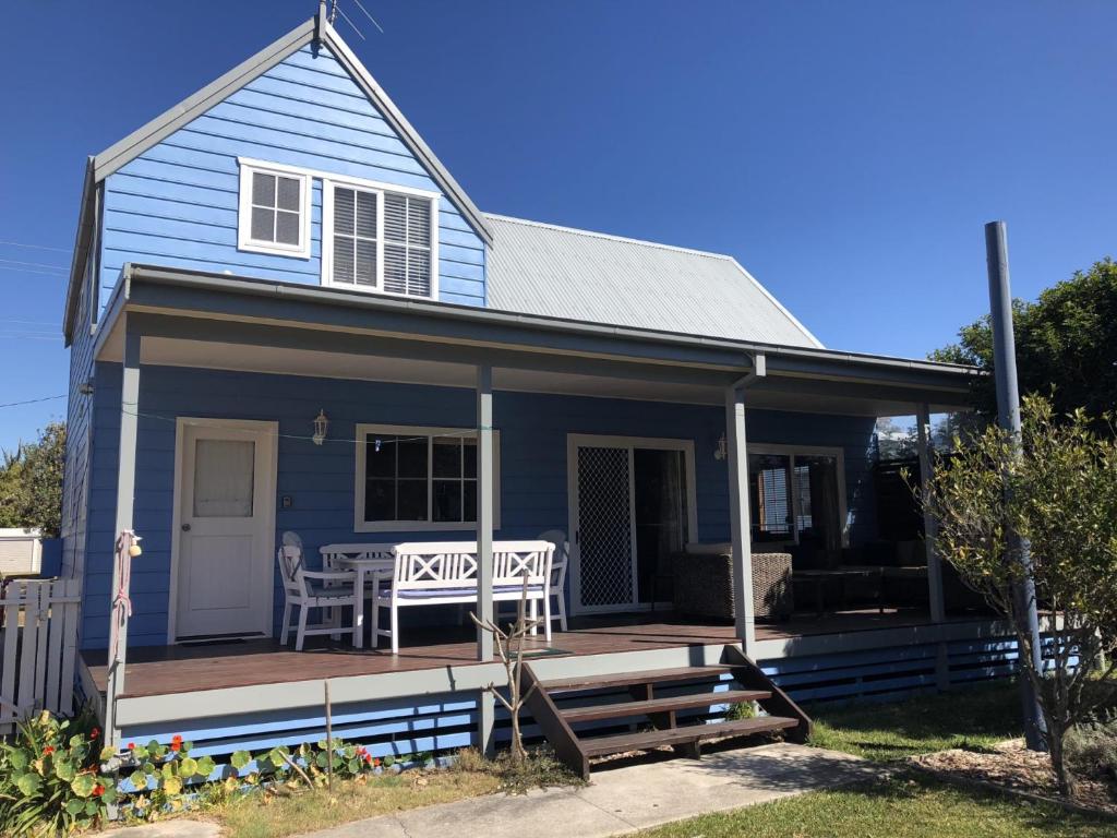 une maison bleue avec une terrasse et une table dans l'établissement Kookaburra Cottage 71 Straight St HH, à Hat Head