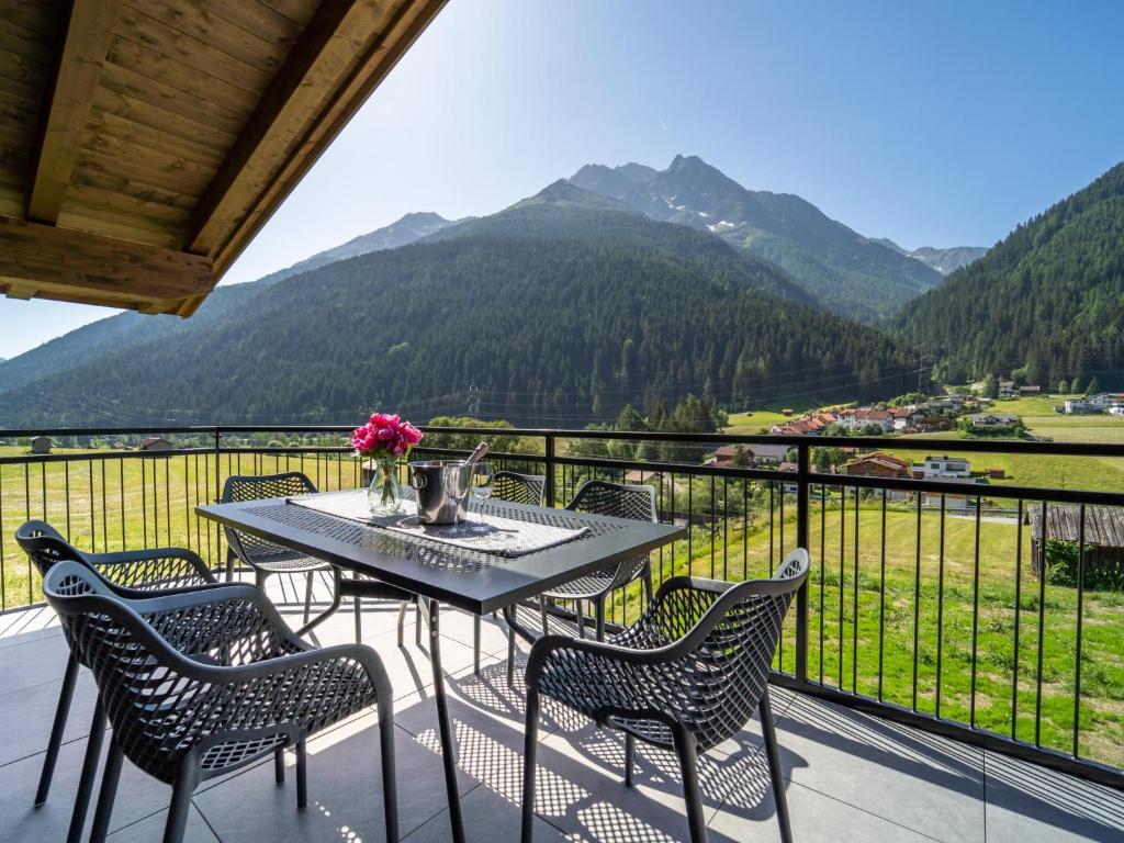ein Tisch und Stühle auf einem Balkon mit Bergen in der Unterkunft Chalet Pettneu am Arlberg - Top 4 in Pettneu am Arlberg