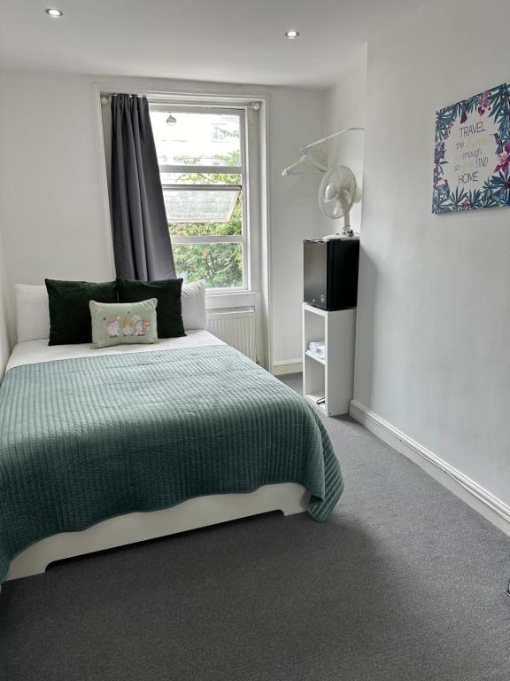 a bedroom with a green bed and a window at LORD MERIT GUEST HOUSE KING'S CROSS GRAYS INN ROAD in London