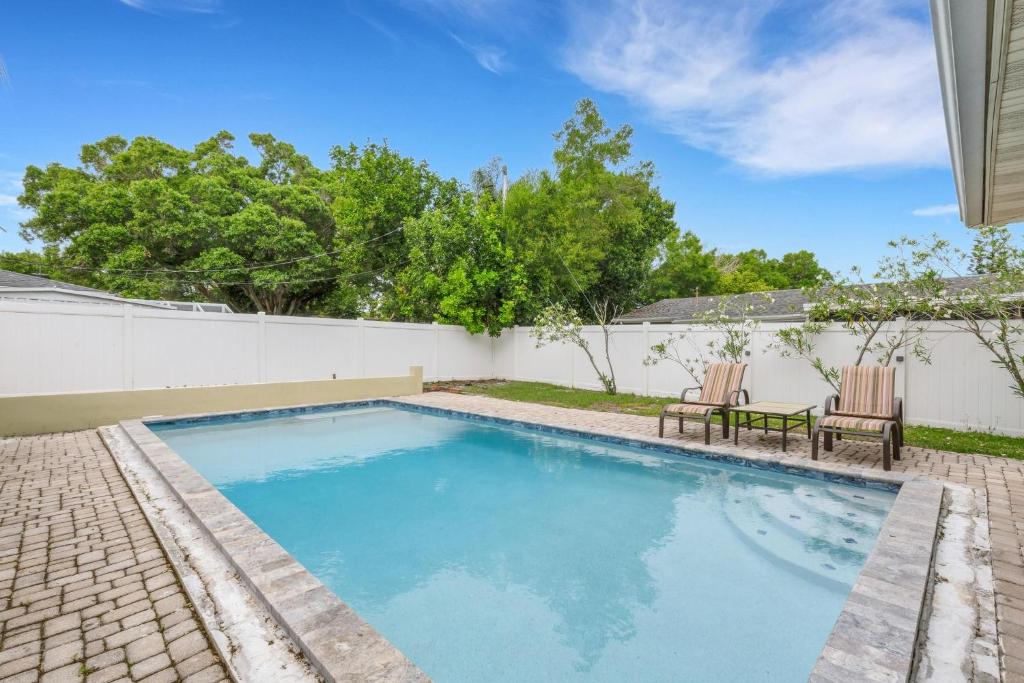 a swimming pool with two chairs next to a fence at Sandy Retreat Pool Home - Vacation Rental in Clearwater