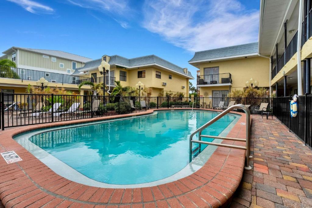 a swimming pool with a fence around a apartment complex at Sunset Corner - Beach View & Heated Pool! in St Pete Beach