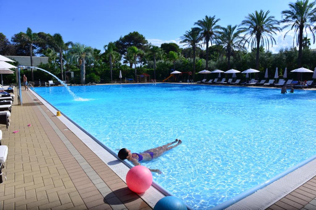 Un uomo sdraiato in una piscina con palloncini di Green Paradise Resort a Otranto