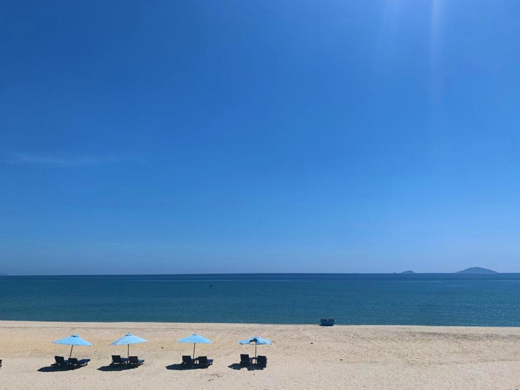 un groupe de chaises et de parasols sur une plage dans l'établissement Heritage AnBang, à Hội An