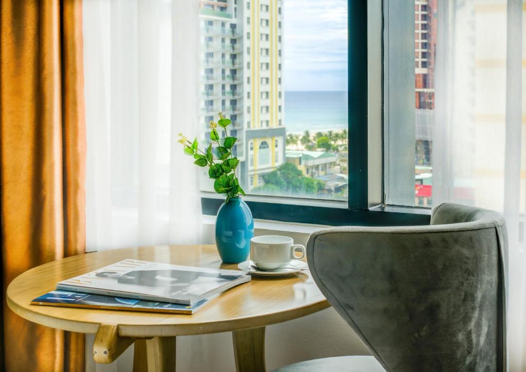 A small round table by the window with a chair, coffee and a partial sea view.