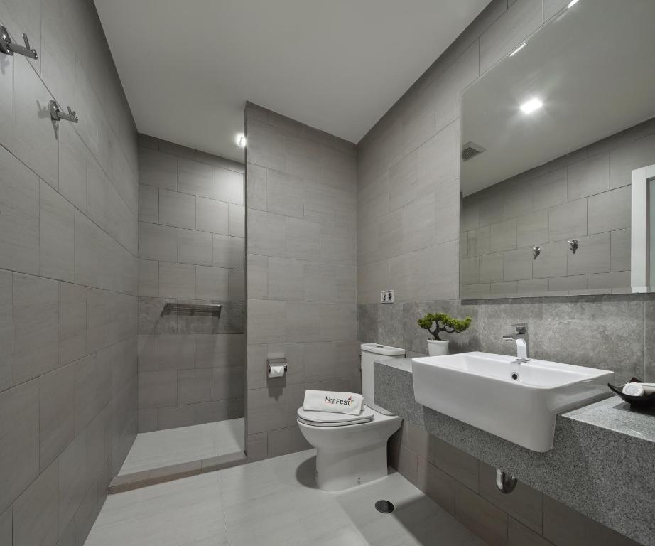 A tiled bathroom with a raised shower, wall mirror and pedestal-style sink.
