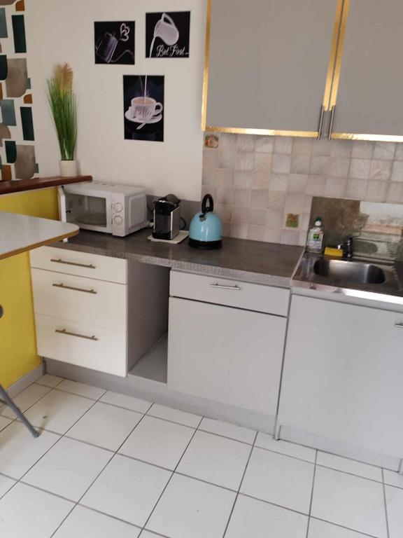 une cuisine avec des armoires blanches et un évier dans l'établissement Or rose 02, à Toulouse