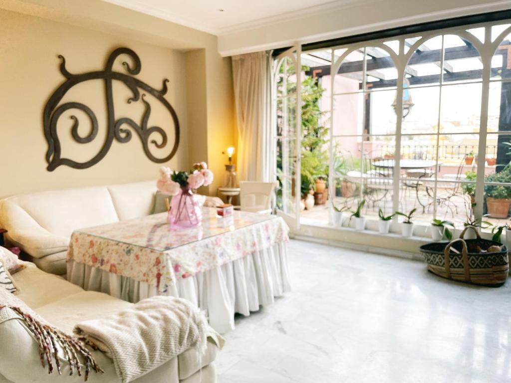 a living room with a table and a large window at Ático la Estrella in Alcalá de Guadaira