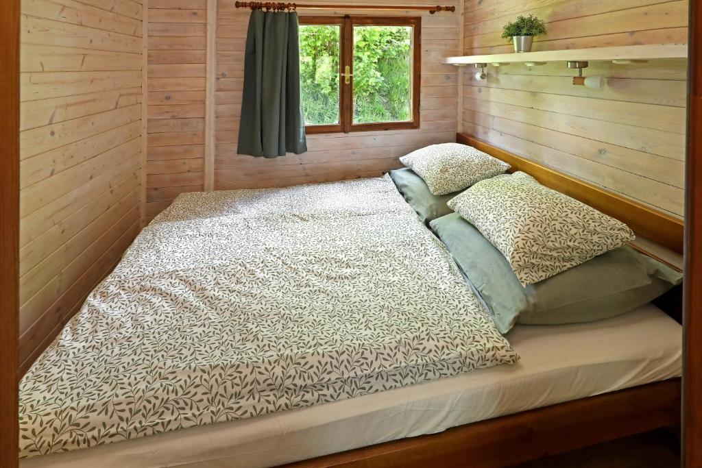 a bed in a log cabin with a window at Lipno Lodge in Horní Planá