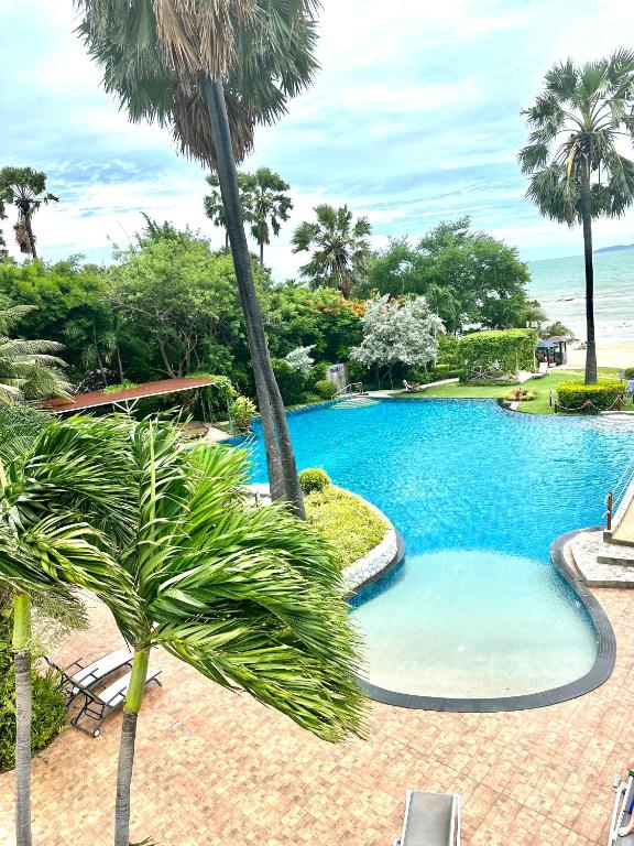 a swimming pool with palm trees in a resort at The Palm Wongamat 22 in North Pattaya