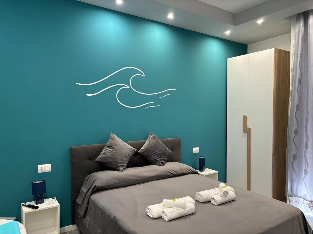 a bedroom with a blue wall with a bed and towels at Appartamento Onda in Lido di Ostia