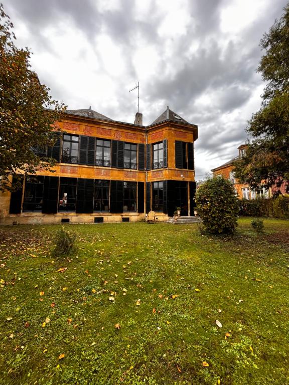un grand bâtiment avec une pelouse devant lui dans l'établissement Ardennes Manoir Blossom, à Vouziers