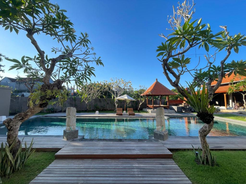 a pool at a resort with trees and a wooden walkway at Kusuma Life in Kerobokan