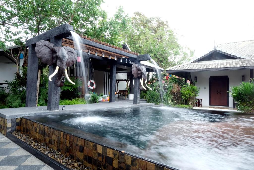清迈Vimarn Kaew Village and Resort的一座房子前面的游泳池,上面有大象喷泉