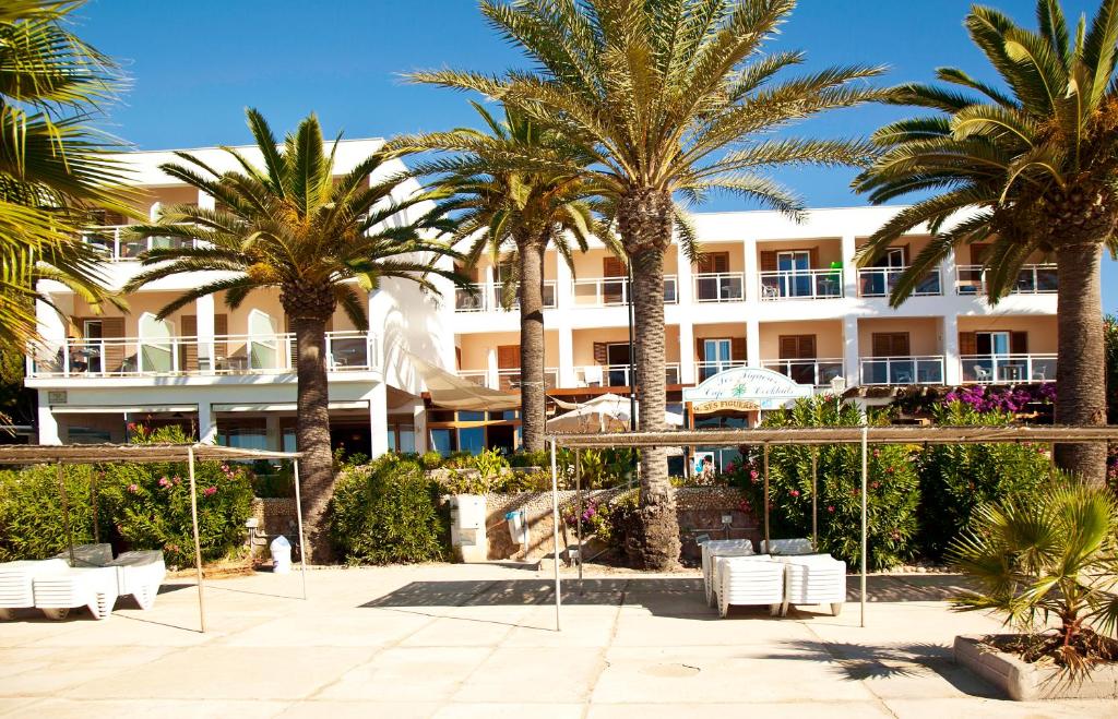 a hotel with palm trees in front of it at Hotel Ses Figueres in Talamanca