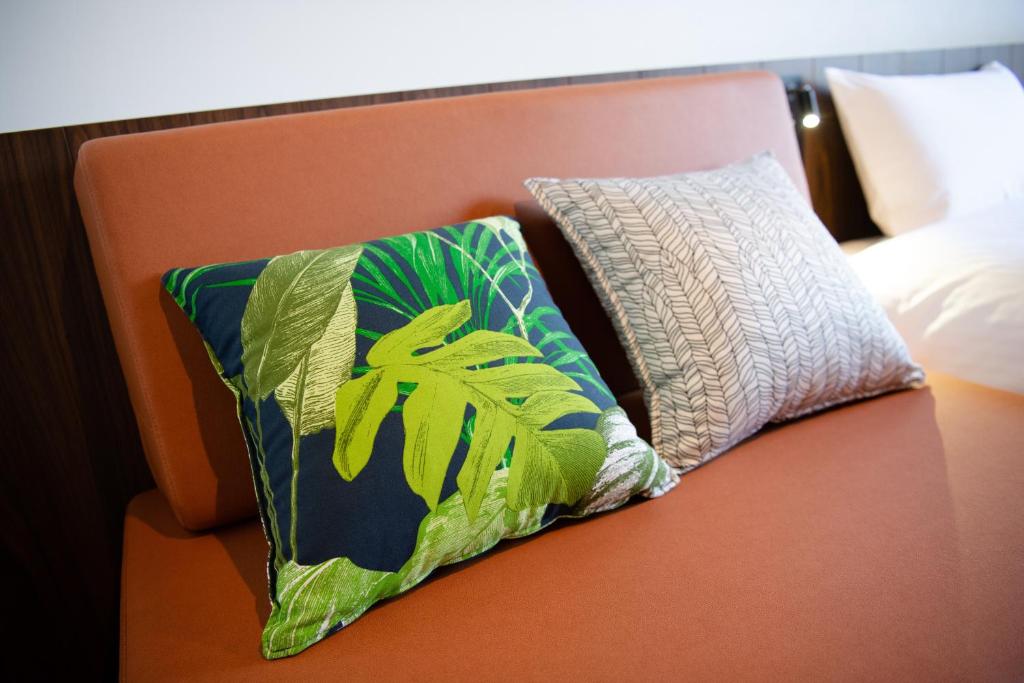 a couch with two pillows on it next to a bed at Henn na Hotel Tokyo Akasaka in Tokyo