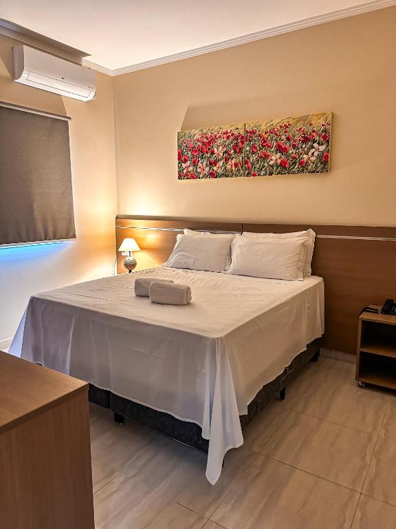 a bedroom with a bed with a painting on the wall at Hotel Stelati in Jaguariúna