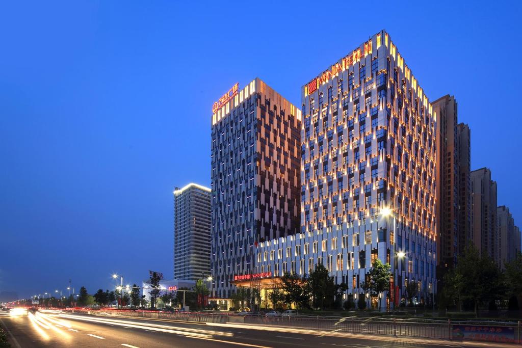 a tall building with many windows on a city street at Anyang Wanda Realm Hotel in Anyang