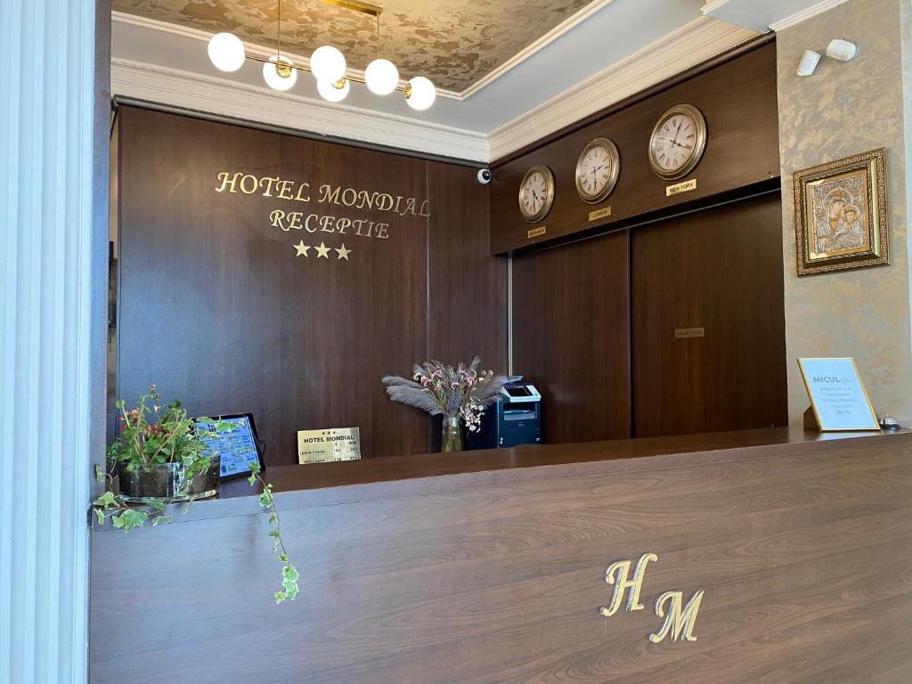 a hotel reception desk with clocks on the wall at Hotel Mondial - Eforie Nord in Eforie Nord