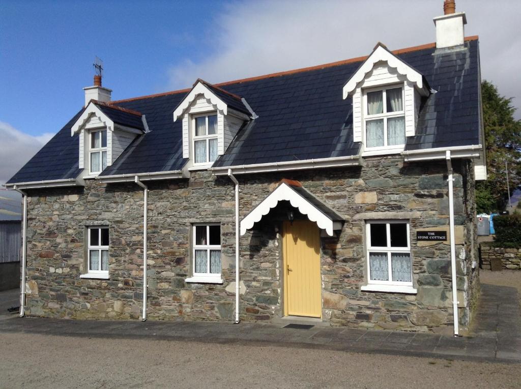 an old stone house with a yellow door at The Stone Cottage in Kenmare