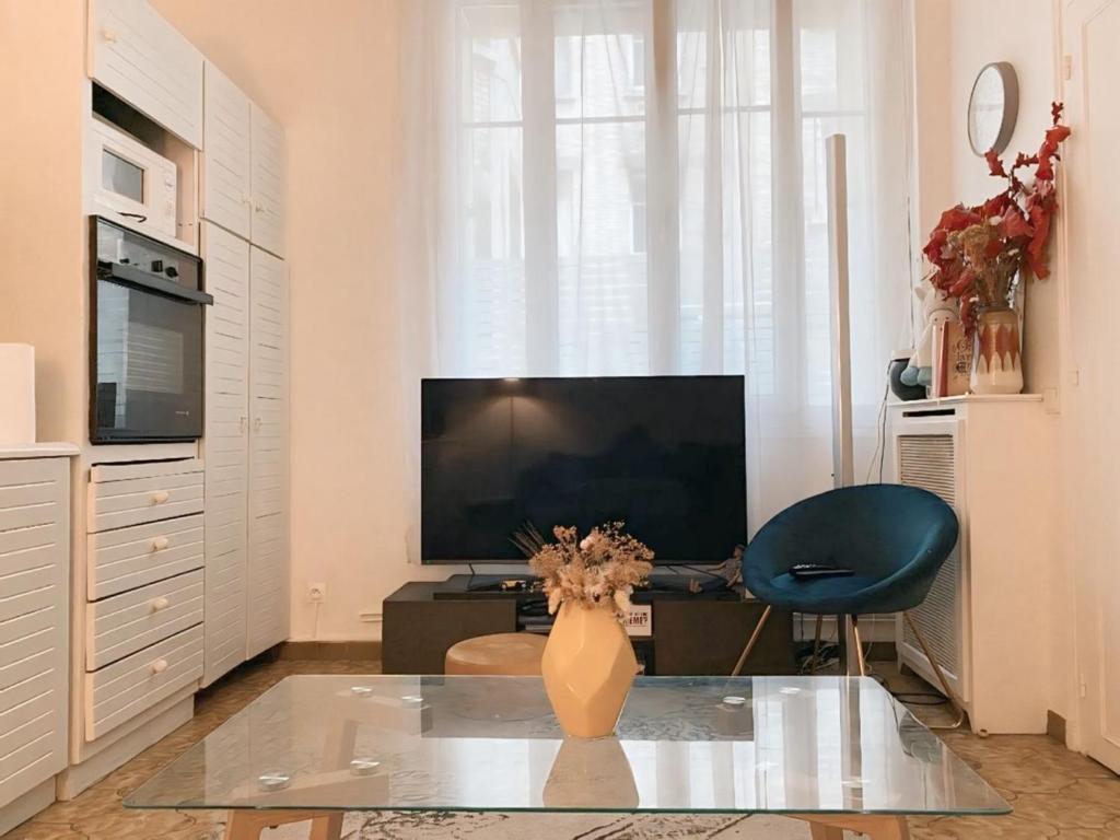 un salon avec une télévision et un vase sur une table dans l'établissement Fontaine, à Paris