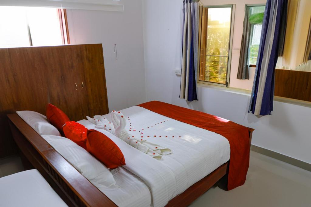 AnachalにあるBuddha Mayuri Homestayのベッドルーム1室(赤と白の枕が備わるベッド1台付)
