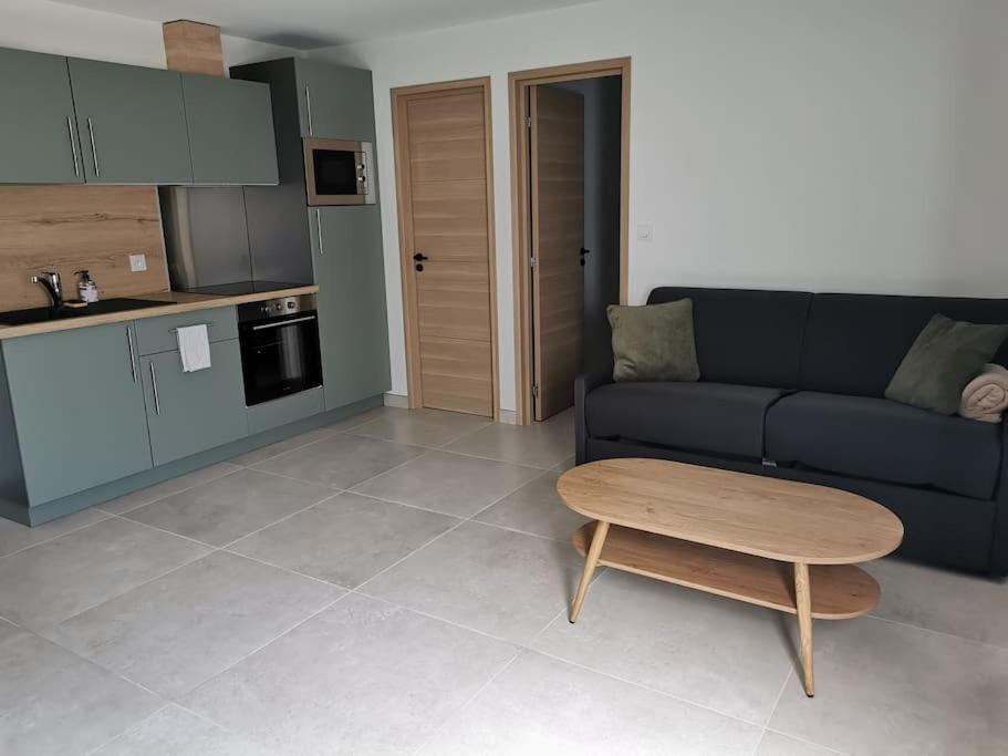 a living room with a black couch and a table at Appartement centre ville rdc in Évreux