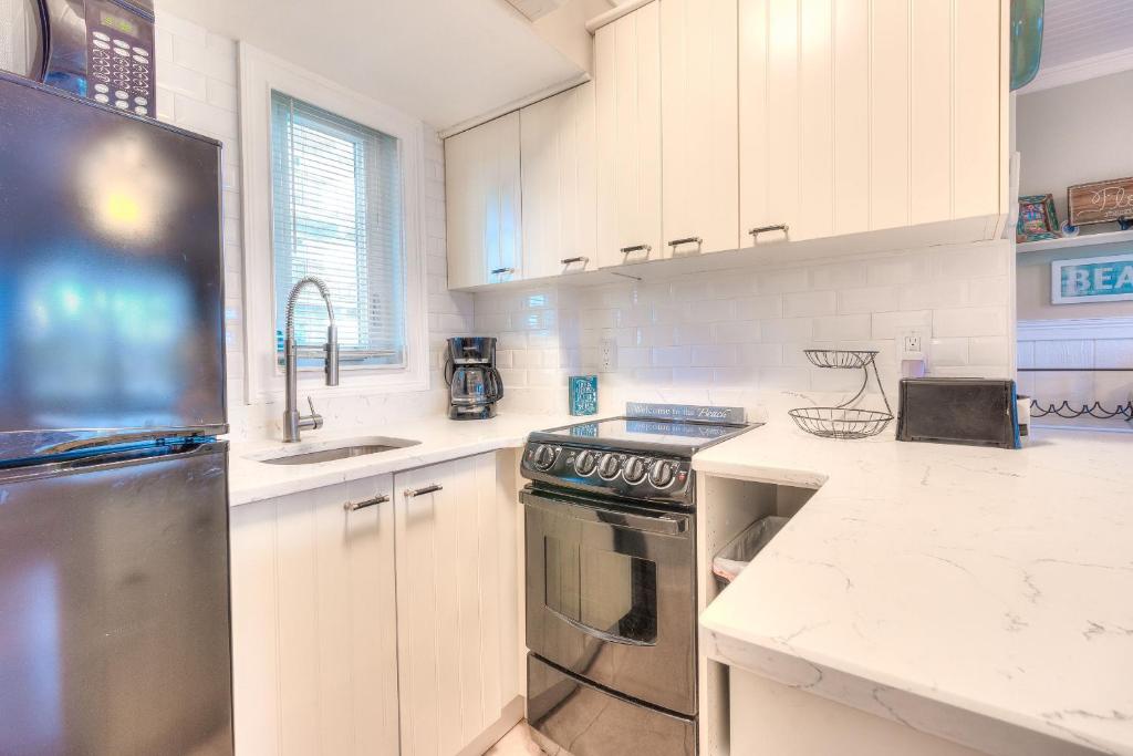 une cuisine avec des armoires blanches et un réfrigérateur en acier inoxydable dans l'établissement Tropic Terrace #32 - Beachfront Rental, à St. Pete Beach