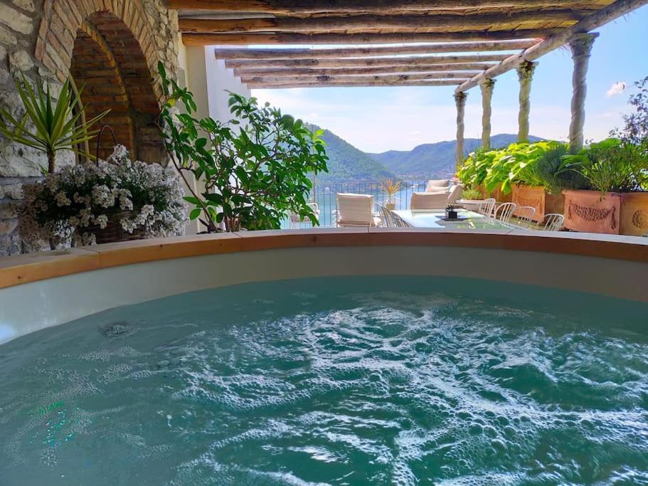 a hot tub on a balcony with a view of the mountains at Il Monsignore - Finnish WoodenJacuzzi and Stunning Lake Views in Cernobbio