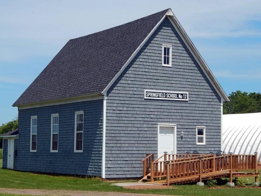 a large blue barn with a wooden porch at Old Schooling Summer Cottage in OʼLeary