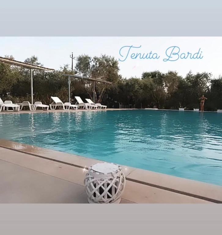 a swimming pool with blue water and white chairs at Tenuta Bardi in Villa Baldassarri