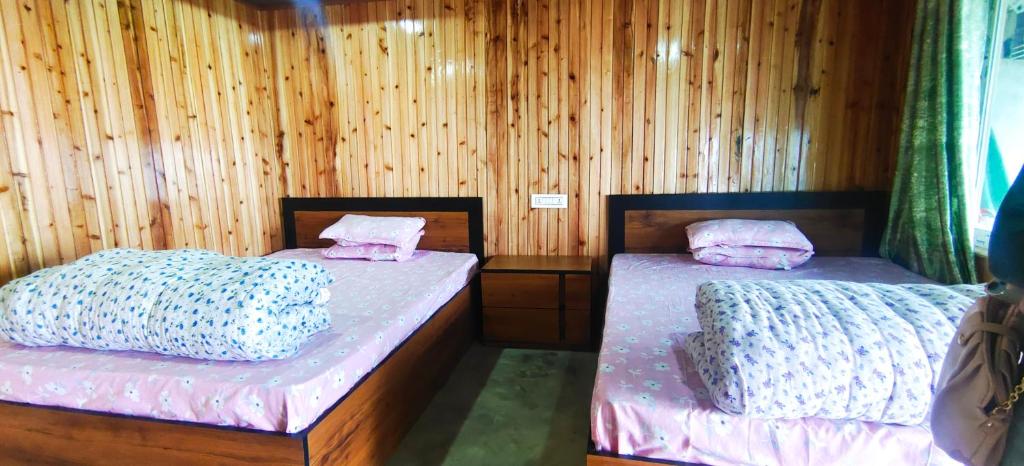 two beds in a room with wooden walls at Zero Points TheLaure Cottage in Ilām