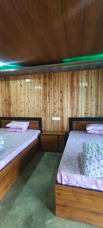 two beds in a room with wooden walls at Zero Points TheLaure Cottage in Ilām