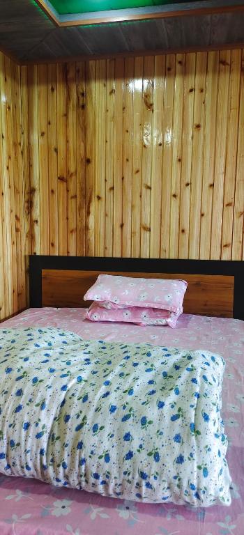a bedroom with a bed with a wooden wall at Zero Points TheLaure Cottage in Ilām