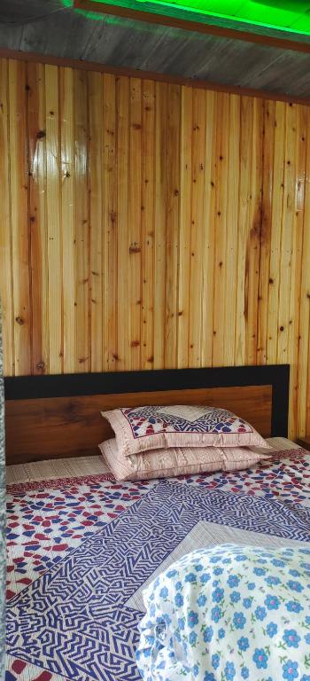 a bedroom with a bed with a wooden wall at Zero Points TheLaure Cottage in Ilām